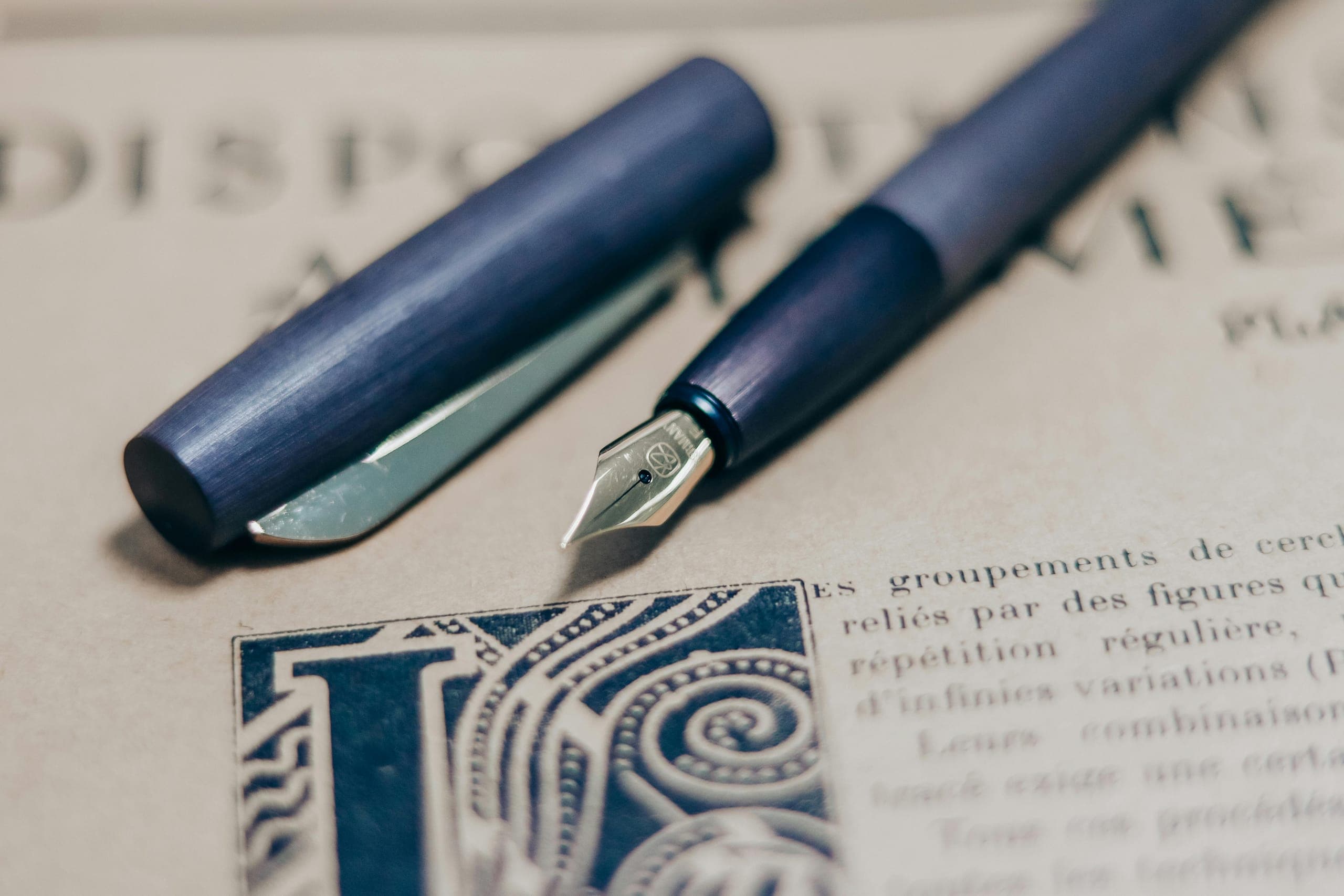 A bound essay on a tutor desk beside a fountain pen